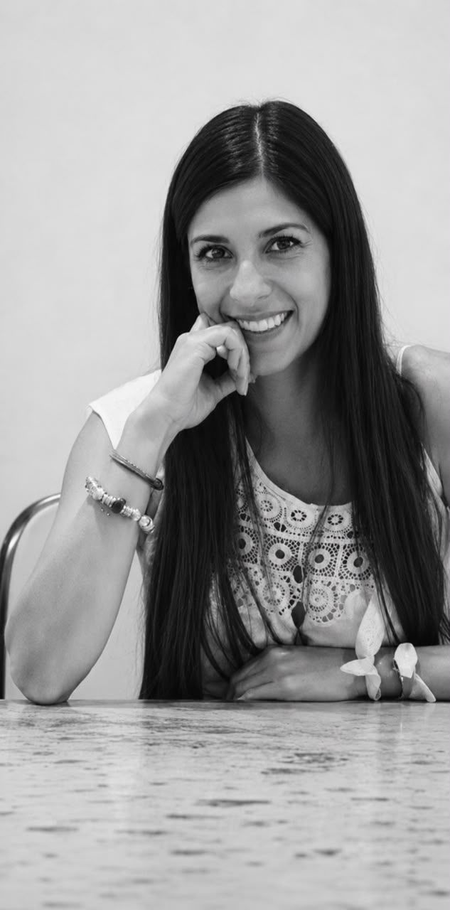 Romina sonriendo, apoyada en una mesa